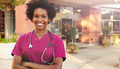 A HUMIRA® Nurse Ambassador smiling in front of a hospital.