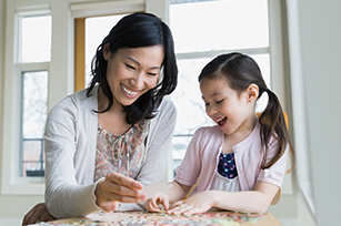 A mom and her daughter are doing a puzzle.