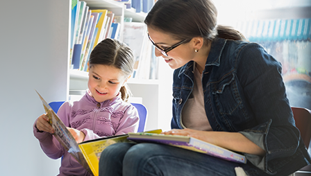 A mom and daughter reading a book at the eye doctor’s office.